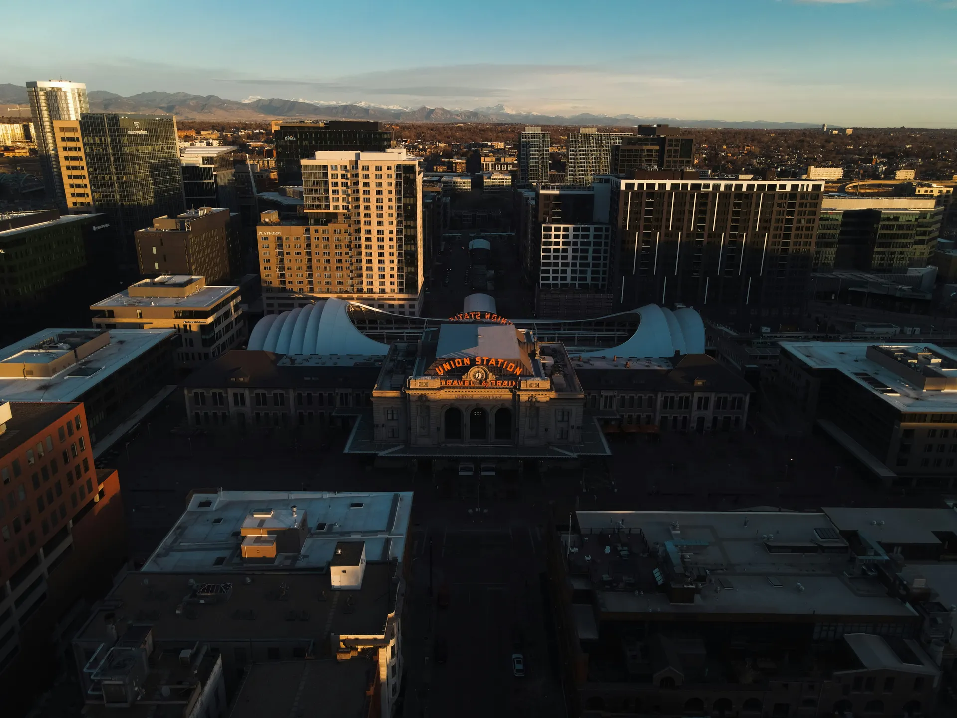 Arial sunrise view of Denver's Union Station. Sunbeams are just beginning to hit the tops of buildings.